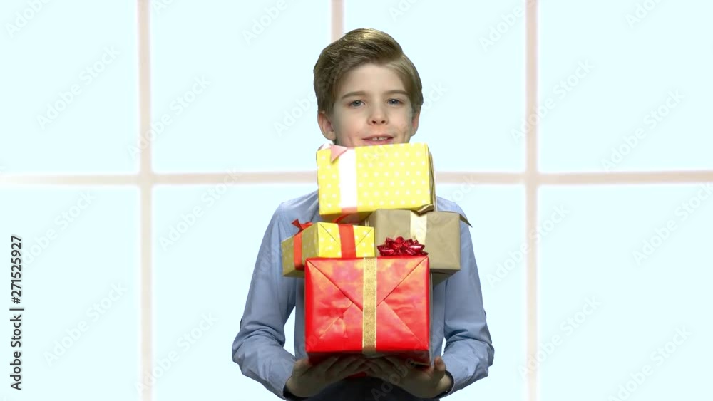 Handsome boy holding group of gift boxes. Cute child with a lot of holiday presents on blurred background. Handsome boy holding group of gift boxes. Cute child with a lot of holiday presents on blurred background.