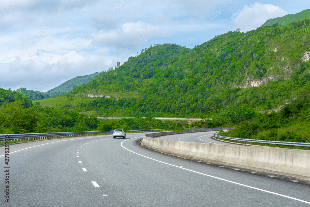 Two lane street/ double lane road on dual carriageway highway through scenic countryside mountain landscape. Vehicles drive on left hand side of the road. Saint Ann/St Ann, Jamaica.