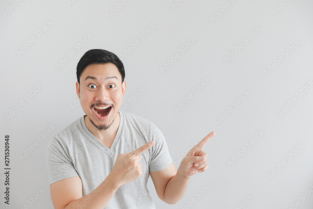 Wow and surprised face of man in grey t-shirt with hand point on empty space. Wow and surprised face of man in grey t-shirt with hand point on empty space.