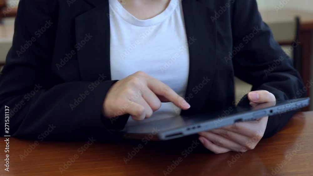 Panning camera shot of business woman in black suit using tablet on wooden table Panning camera shot of business woman in black suit using tablet on wooden table