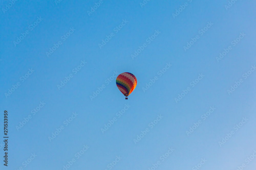 Fototapeta premium Colorful hot air balloon is flying in blue sky 