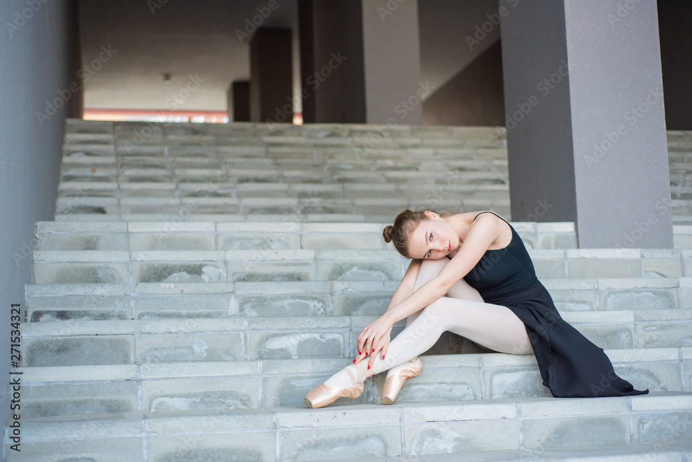 Ballerina in tutu posing sitting on the stairs A beautiful young woman in a black dress and pointe shoes is resting sitting in an elegant pose on the stairs from the outside Ballerina in tutu posing sitting on the stairs A beautiful young woman in a black dress and pointe shoes is resting sitting in an elegant pose on the stairs from the outside