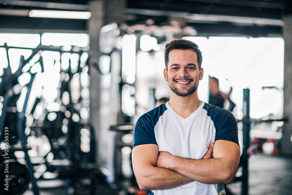 Portrait of a smiling young man in sportswear in the gym, looking at camera.