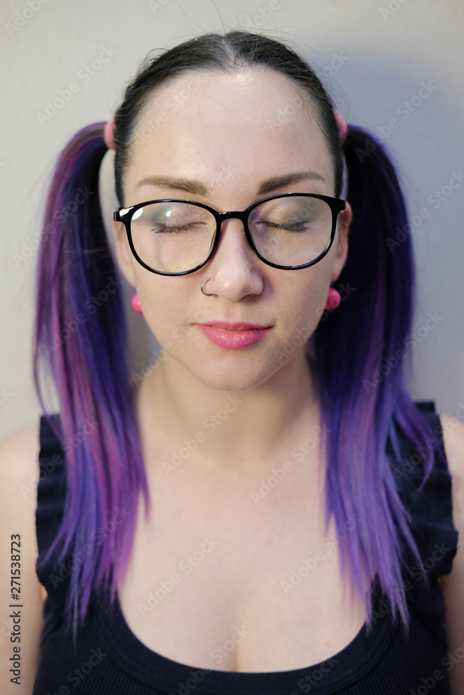 Young woman with purple hair and black glasses.