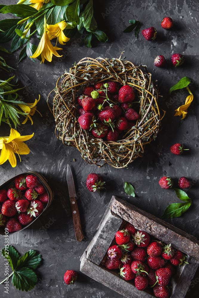 Delicious strawberries with yellow flowers on a dark gray background in a vintage wreath. Healthy