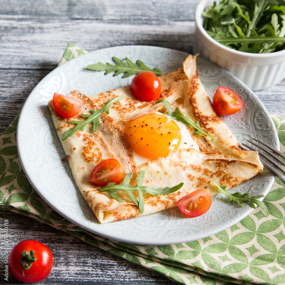 Crepes with eggs, cheese, arugula leaves and tomatoes. Galette complete. Traditional dish galette sarrasin. Crepes with eggs, cheese, arugula leaves and tomatoes. Galette complete. Traditional dish galette sarrasin.