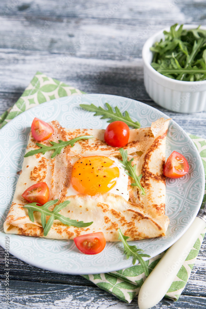 Crepes with eggs, cheese, arugula leaves and tomatoes. Galette complete. Traditional dish galette sarrasin. Crepes with eggs, cheese, arugula leaves and tomatoes. Galette complete. Traditional dish galette sarrasin.