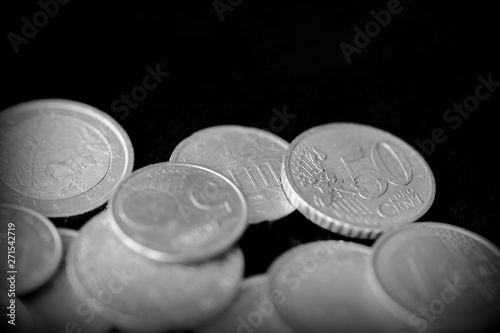 Euro coins scattered on a dark surface close up. Black and white