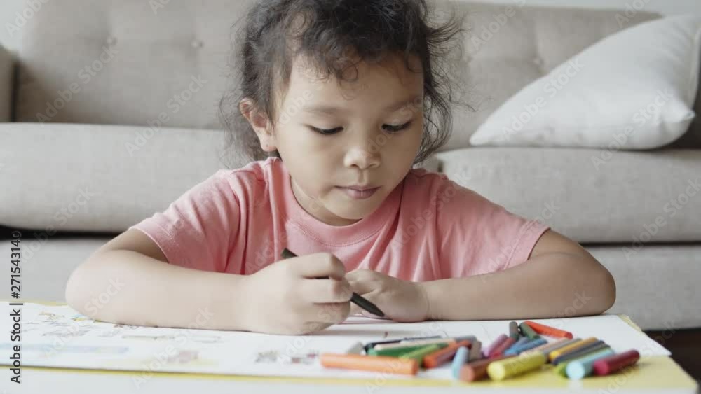 A cute Asian girl sitting, drawing and painting happily at her home. A cute Asian girl sitting, drawing and painting happily at her home.