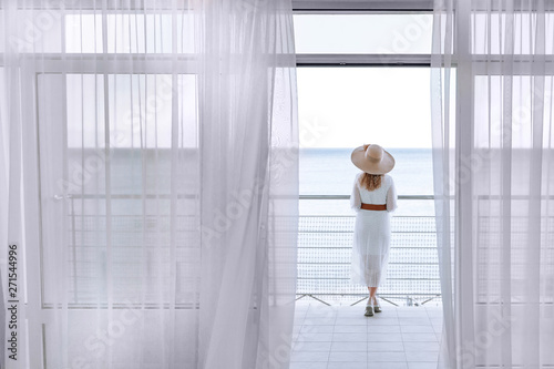Photography A woman enjoys the view of the sea with a beautiful view from the terrace in the early summer morning