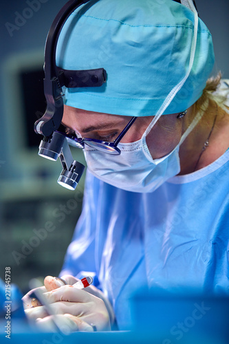 Close up portrait of female surgeon doctor wearing protective mask and hat during the operation. Healthcare, medical education, surgery concept. © Georgii