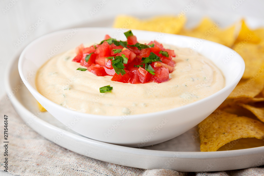 Homemade cheesy dip in a bowl, yellow tortilla chips, side view. Close-up. Homemade cheesy dip in a bowl, yellow tortilla chips, side view. Close-up.