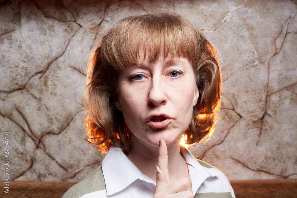 Portrait of a middle-aged blonde woman and a wall behind Portrait of a middle-aged blonde woman and a wall behind
