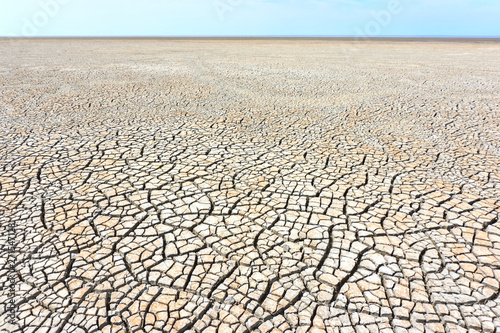 Desolate landscape with cracked ground at the seashore. Brown, beige, light tan and grey colored. Concept of global warming. 