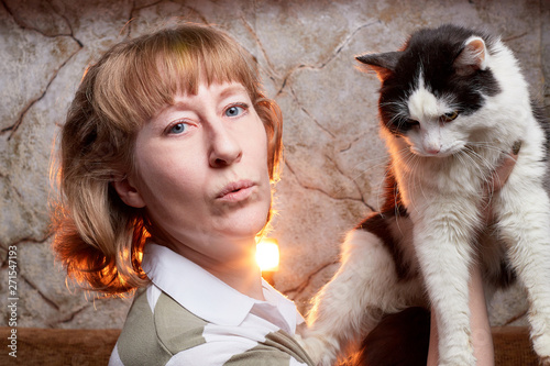 Portrait of a middle-aged blonde woman with cat and a wall behind