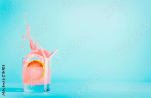 Obraz Grapefruitowy napój w szkle z pluśnięciem na błękitnym tle. Letni orzeźwiający napój. Różowa lemoniada grejpfrutowa. Skopiuj miejsce