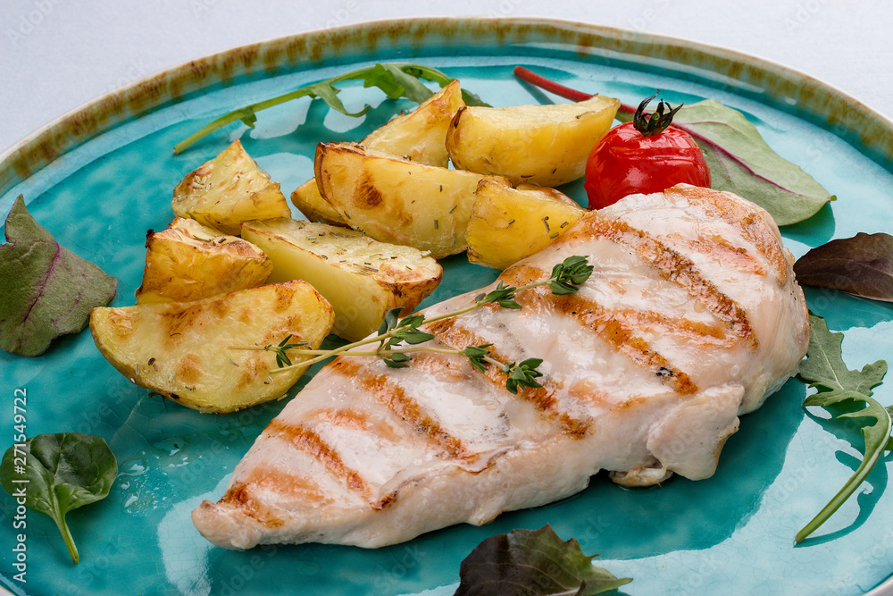 Grilled chicken fillet with fried potatoes. On light background