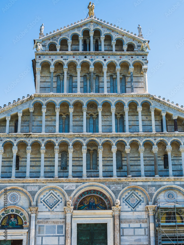 Facade details of the Medieval Roman Catholic Cathedral in a Romanesque architectural style in the Piazza dei Miracoli, Pisa, Italy, with scaffolding for restoration at the base.