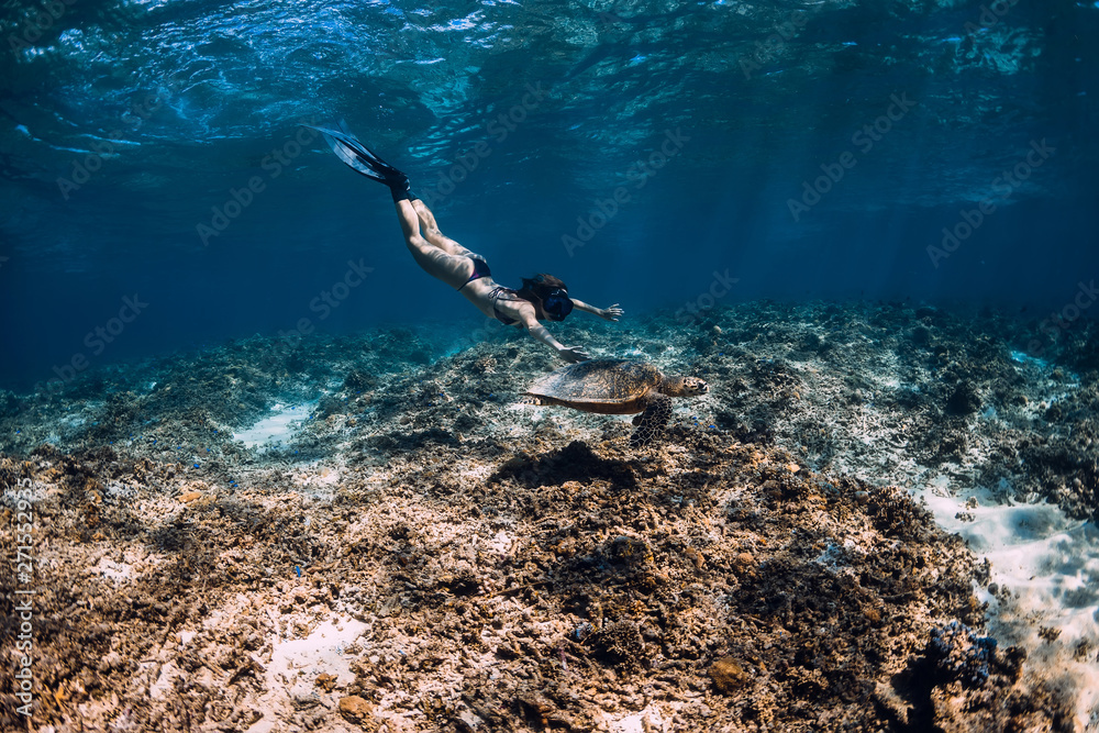 Woman freediver swim underwater with sea turtle.