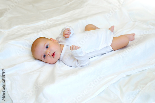 Cheerful baby boy newborn 3 months lying on a white bed.