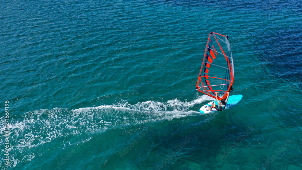 Aerial top view photo of fit man practising wind surfing in Mediterranean bay with crystal clear emerald sea Aerial top view photo of fit man practising wind surfing in Mediterranean bay with crystal clear emerald sea