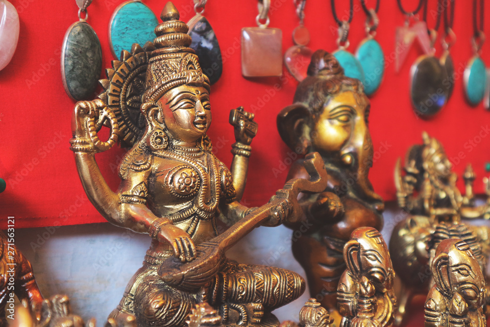 Bronze figure of the goddess of wisdom Saraswati on a red background in a souvenir shop in India.