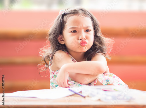 Photography Angry little cute girl with cross one's arm