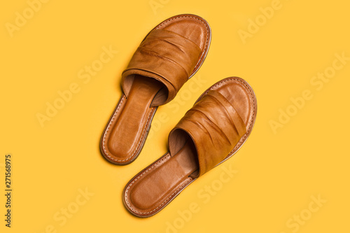 Sandalias para mujer de cuero marrón sobre fondo amarillo liso aislado. Vista superior. Copy space