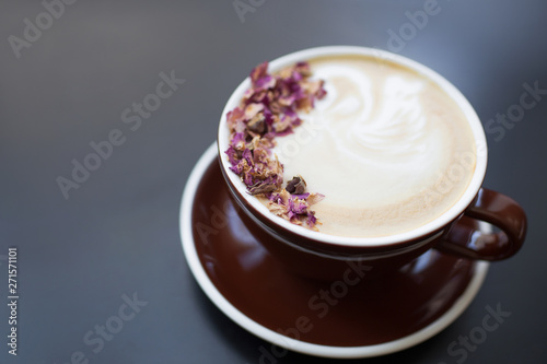 Cup of coffee on black rustic background with beautiful latte. Coffee foam with flowers. Cappuccino. 