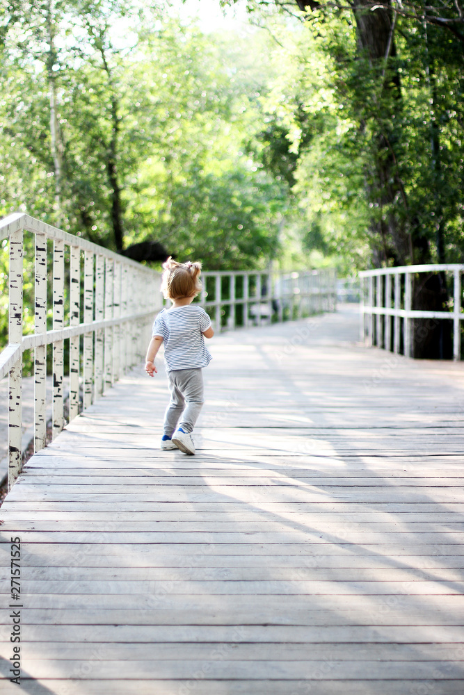 The child runs through the woods on a wooden bridge. The child walks in the park The child runs through the woods on a wooden bridge. The child walks in the park