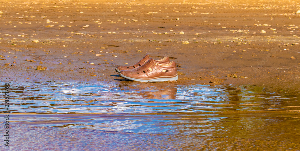 Fototapeta premium brown shoes on the edge of the shore near the water