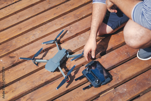 Male hands collecting drone on wooden background.