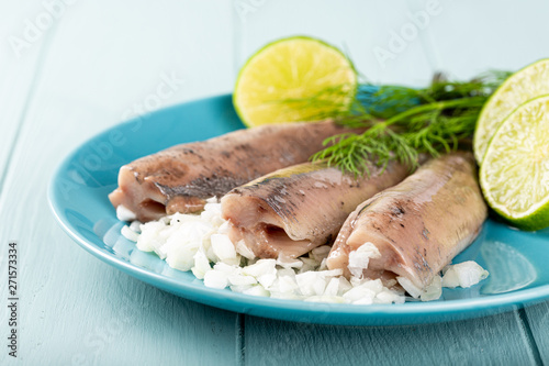 Photography Traditional dutch food freshly salted herring fish with onion called hollandse nieuwe on turquoise plate and wooden background