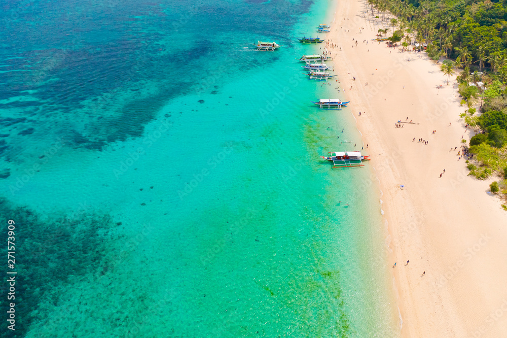 Puka Shell Beach, Boracay Island, Philippines, aerial view. Tropical white sand beach and beautiful lagoon. Tourist boats and people on the beach. People relax on the beautiful coast.