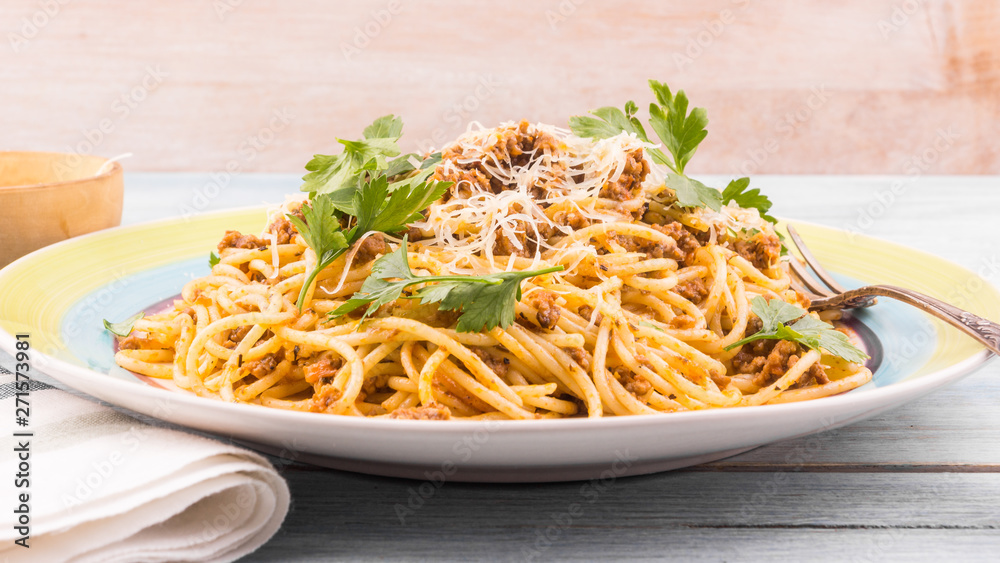 Portion of traditional Italian pasta on a plate close up - spaghetti bolognese with parmesan and parsley