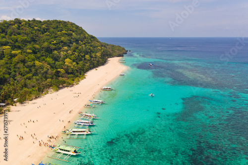 Puka Shell Beach. Wide tropical beach with white sand. Beautiful white beach and azure water on Boracay island, Philippines, top view. Tourists relax on the beach.