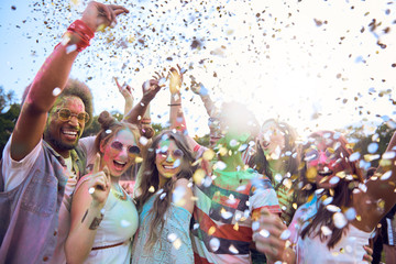 Friends celebrating holi festival under shower of confetti
