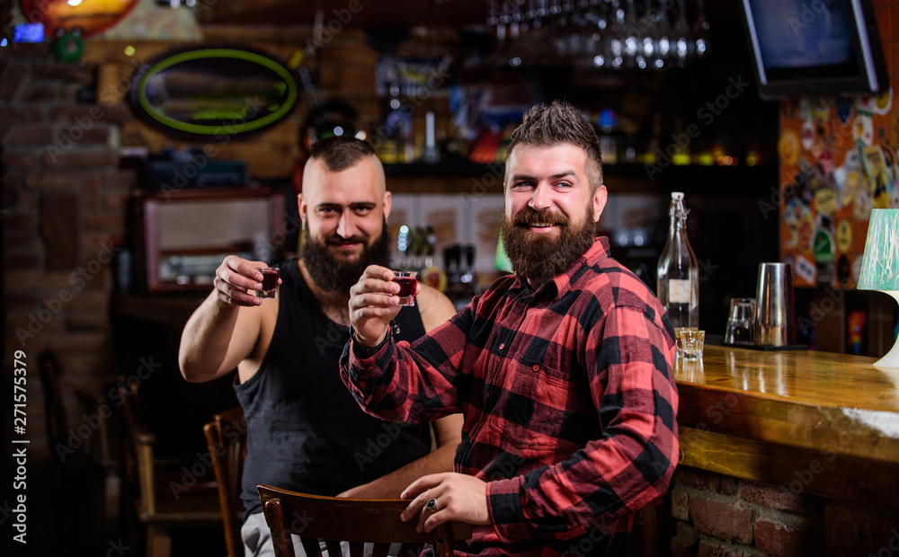 Men relaxing at bar. Friendship and leisure. Friday relaxation in bar. Friends relaxing in pub. Hipster brutal bearded man spend leisure with friend at bar counter. Order drinks at bar counter