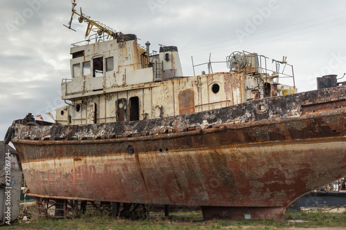 Rusty decommissioned marine ship that was left on the shore.