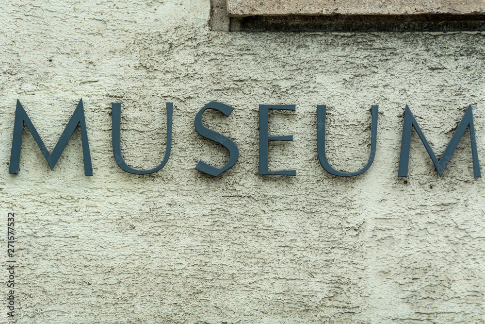 Weathered metal museum sign on plaster wall Weathered metal museum sign on plaster wall