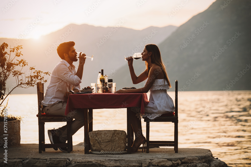 Couple is having a private event dinner on a tropical beach during sunset time - obrazy, fototapety, plakaty 