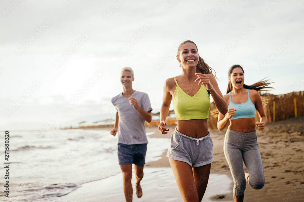 Group of people, friends running on the beach at sunset Group of people, friends running on the beach at sunset