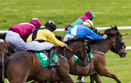 Close up on group of jockeys and race horses racing on track