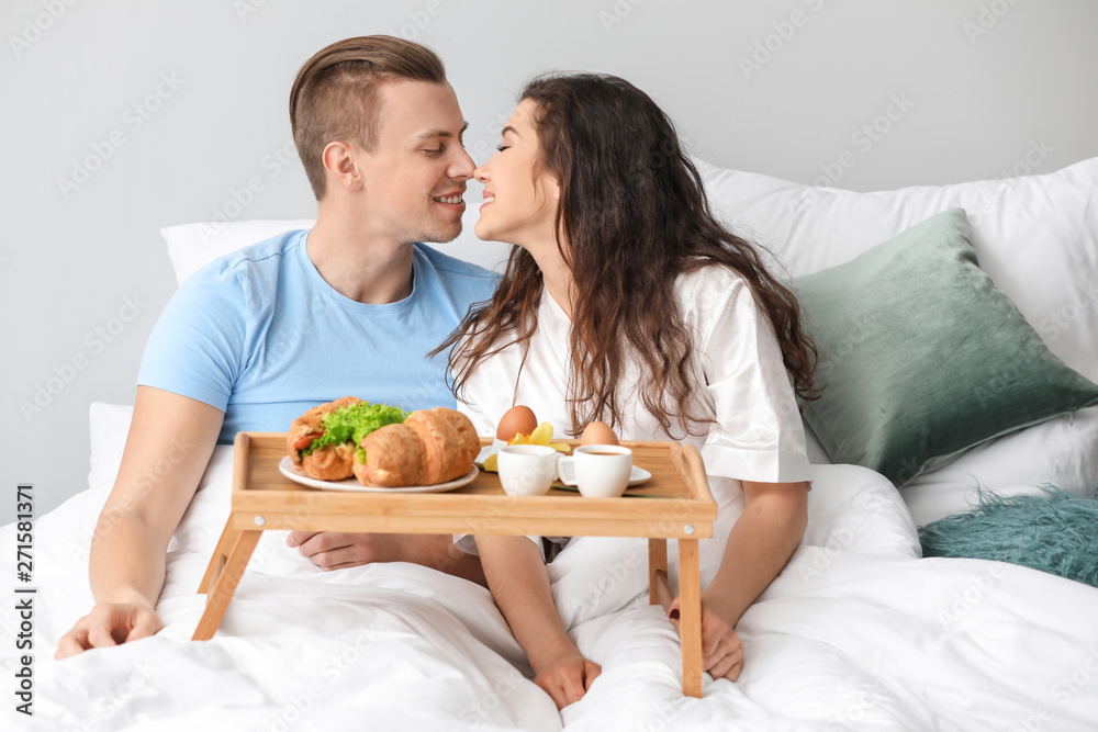 Cute young couple having breakfast in bed