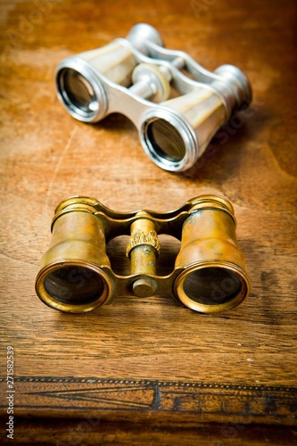 Vintage brass and silver binoculars on old wooden table.