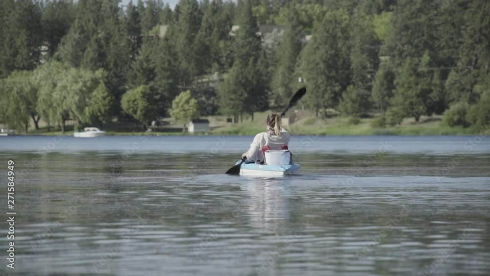Woman rows away in kayak on lake Woman rows away in kayak on lake