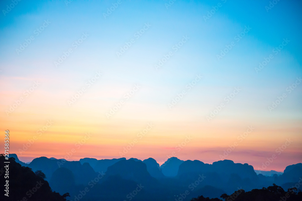 Fototapeta premium Landscape with beautiful dramatic sunset and silhouette of blue mountains at horizon, Thailand