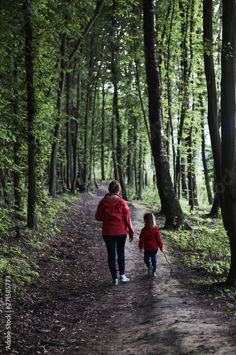 Mother with her little daughter walking through the forest