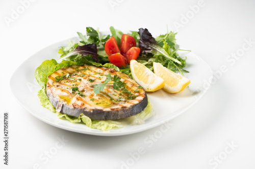 Grilled wordfish with salad and lemon on the white plate