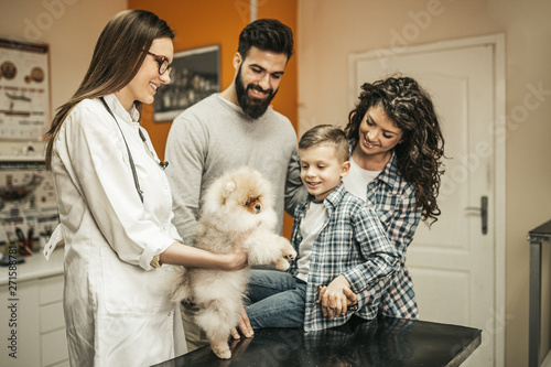 Fototapeta Naklejka Na Ścianę i Meble -  Happy family with their pomeranian dog at veterinary.